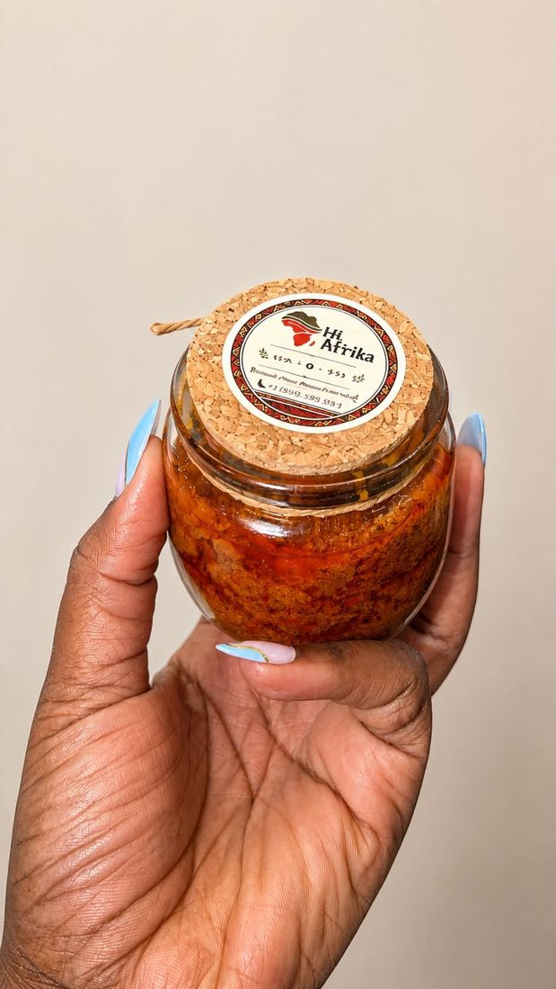 Pot de piment Hi Afrika tenu en main